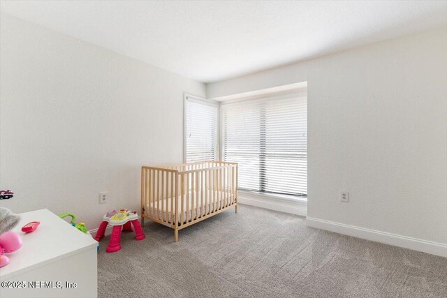 unfurnished bedroom featuring baseboards, carpet, and a crib