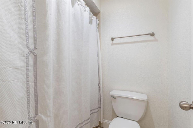 bathroom with curtained shower and toilet