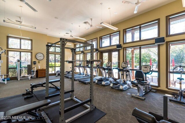 gym with carpet flooring, french doors, visible vents, and a towering ceiling