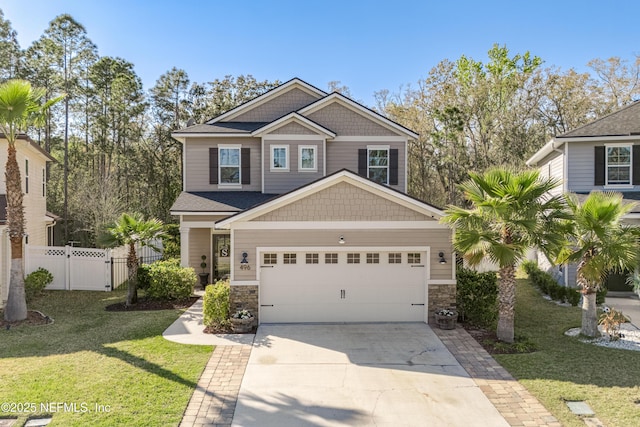 view of front of house with stone siding, concrete driveway, a front lawn, and fence