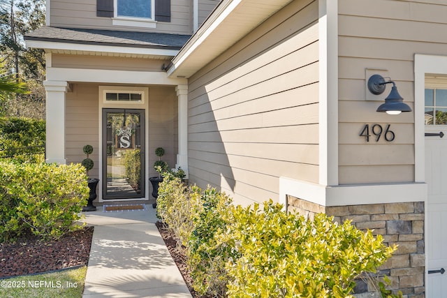 property entrance featuring a shingled roof