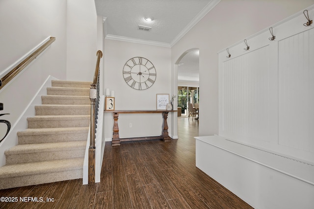 interior space with wood finished floors, visible vents, arched walkways, ornamental molding, and a textured ceiling