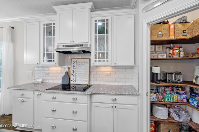 kitchen with under cabinet range hood, black electric stovetop, and white cabinetry