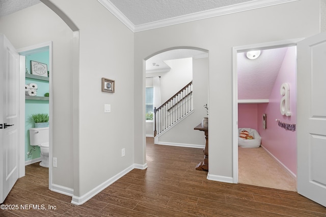 corridor featuring arched walkways, a textured ceiling, wood finished floors, and crown molding