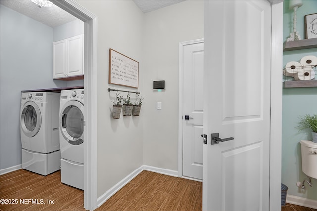 clothes washing area featuring baseboards, wood finished floors, cabinet space, a textured ceiling, and independent washer and dryer