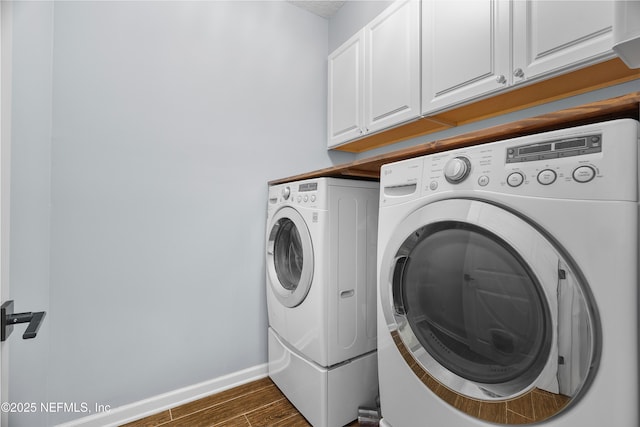 clothes washing area with baseboards, cabinet space, washing machine and dryer, and dark wood finished floors