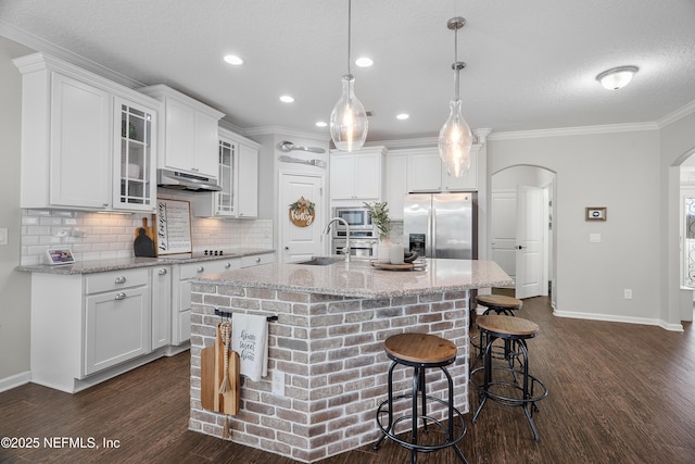 kitchen featuring white cabinets, arched walkways, under cabinet range hood, and stainless steel appliances