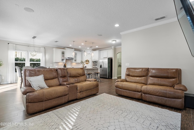 living area featuring dark wood-style floors, visible vents, a textured ceiling, and ornamental molding