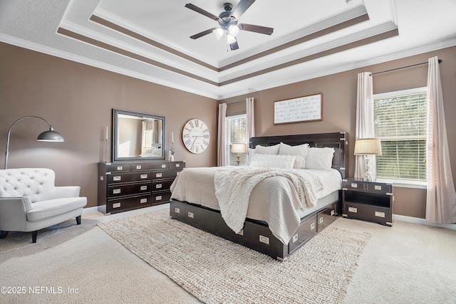 carpeted bedroom with ceiling fan, baseboards, crown molding, and a tray ceiling