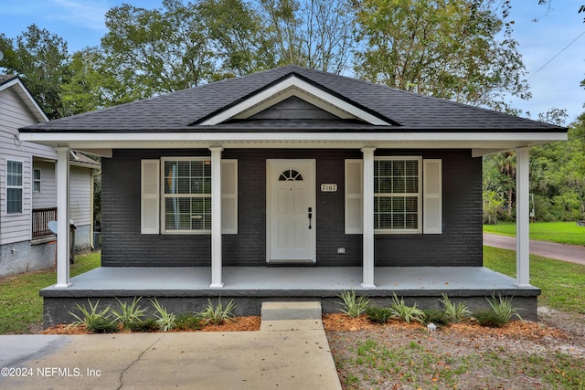 bungalow-style house with brick siding, a porch, and a shingled roof