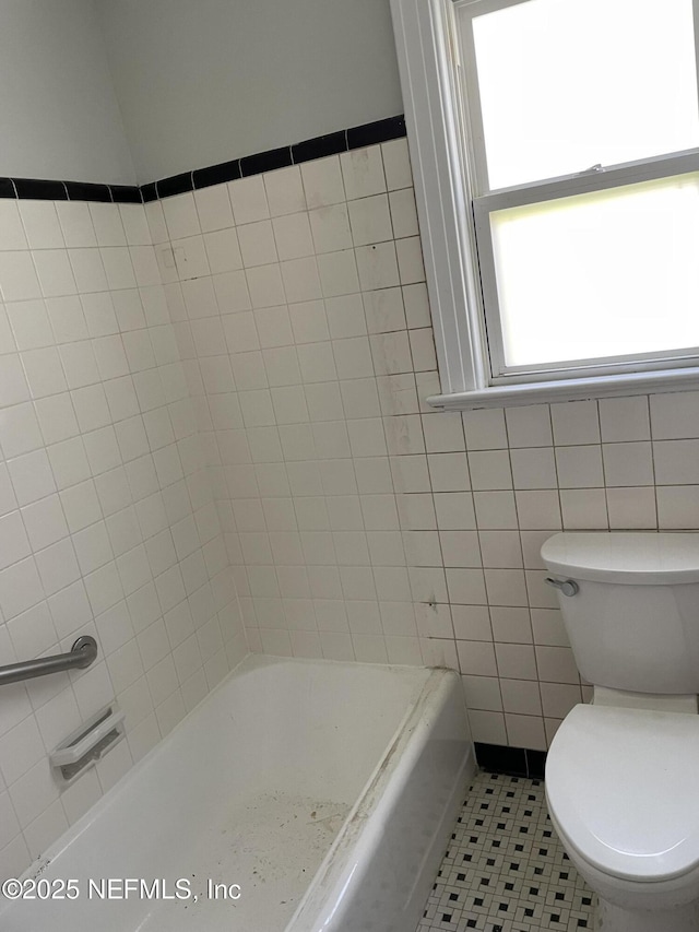 full bath with tile patterned floors, toilet, and tile walls