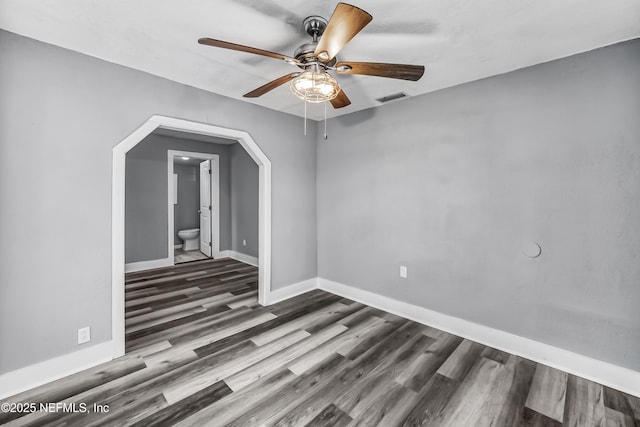 empty room featuring a ceiling fan, wood finished floors, visible vents, and baseboards