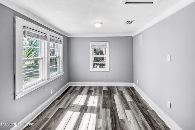 empty room with visible vents, dark wood-type flooring, and baseboards