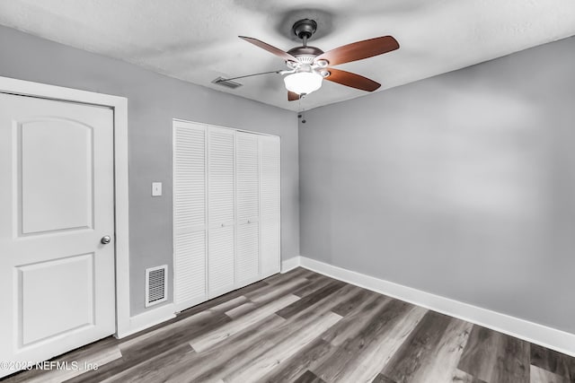 unfurnished bedroom with dark wood finished floors, baseboards, visible vents, and a closet