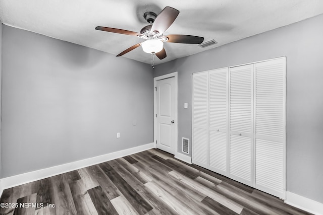 unfurnished bedroom with visible vents, dark wood-type flooring, and baseboards