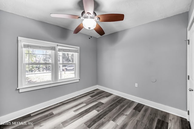 unfurnished room featuring ceiling fan, baseboards, and dark wood finished floors