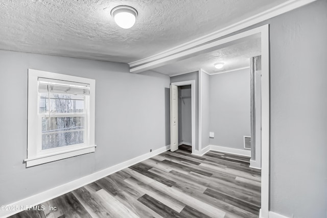 unfurnished bedroom featuring visible vents, baseboards, a textured ceiling, and wood finished floors