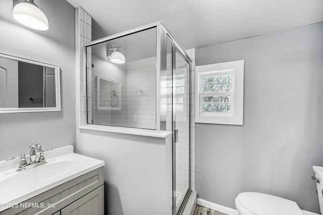 full bathroom featuring vanity, a shower stall, toilet, and baseboards