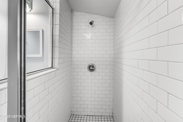 full bathroom featuring lofted ceiling, tile walls, and tiled shower