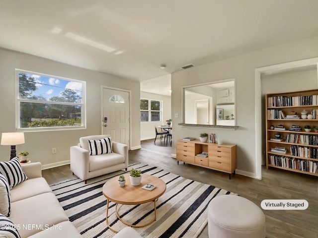 living area with visible vents, plenty of natural light, and wood finished floors