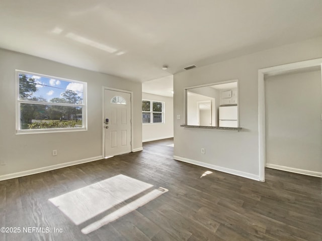 interior space with baseboards, visible vents, and dark wood-style flooring