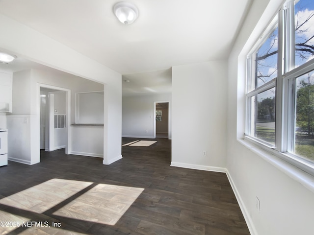 unfurnished living room with baseboards and dark wood-type flooring