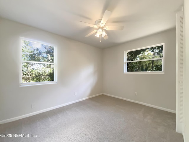 carpeted spare room featuring baseboards and ceiling fan