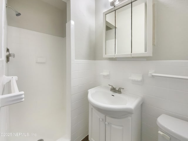 full bathroom with vanity, a shower stall, wainscoting, tile walls, and toilet