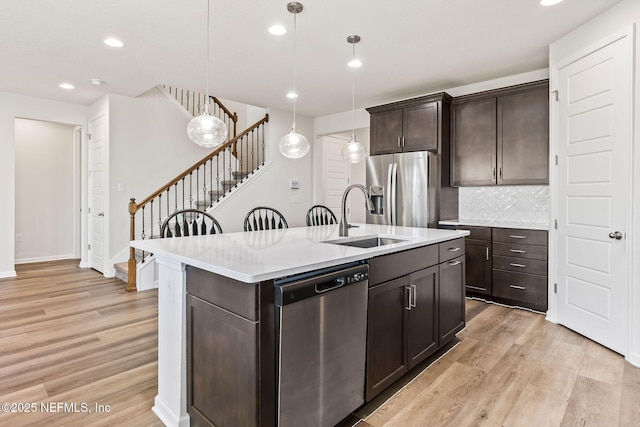 kitchen with a sink, stainless steel appliances, light wood-type flooring, and dark brown cabinets