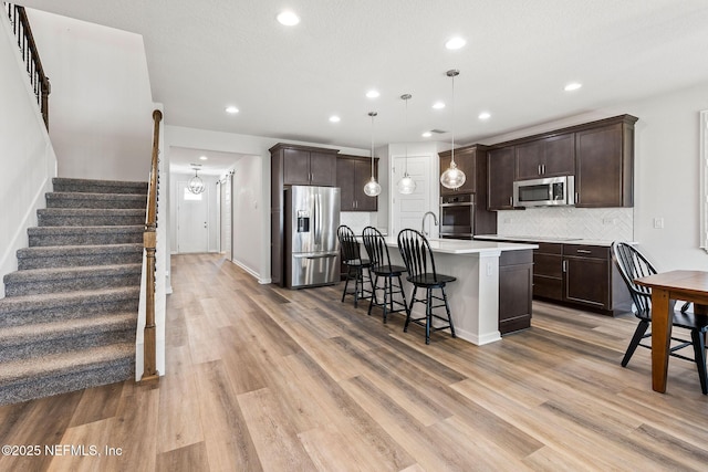 kitchen featuring decorative backsplash, dark brown cabinetry, and stainless steel appliances