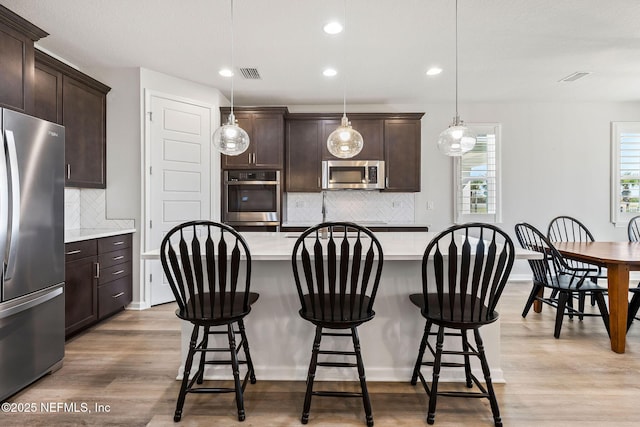 kitchen with visible vents, dark brown cabinets, light wood-type flooring, light countertops, and appliances with stainless steel finishes