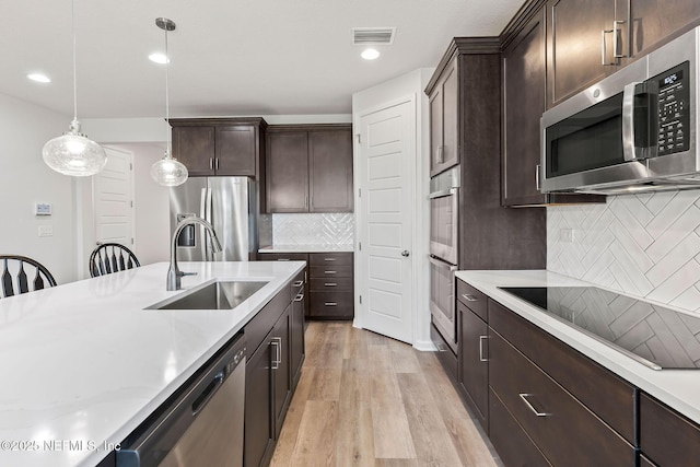 kitchen featuring visible vents, light wood-type flooring, a sink, appliances with stainless steel finishes, and dark brown cabinets