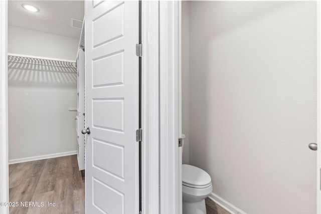 bathroom with toilet, baseboards, and wood finished floors