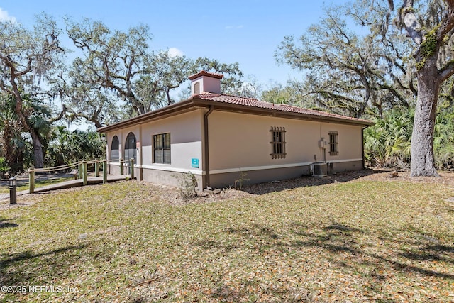 view of side of home with a tile roof, stucco siding, and a lawn