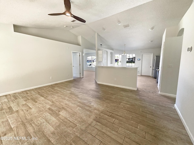 unfurnished living room featuring a ceiling fan, lofted ceiling, wood finished floors, and a textured ceiling