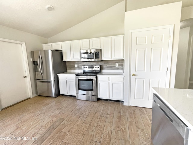 kitchen with lofted ceiling, white cabinets, and appliances with stainless steel finishes