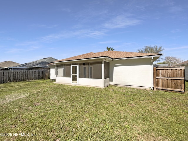 back of property with a gate, fence, a yard, a sunroom, and stucco siding