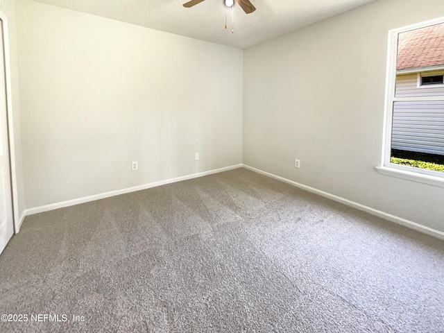 carpeted empty room with a ceiling fan and baseboards