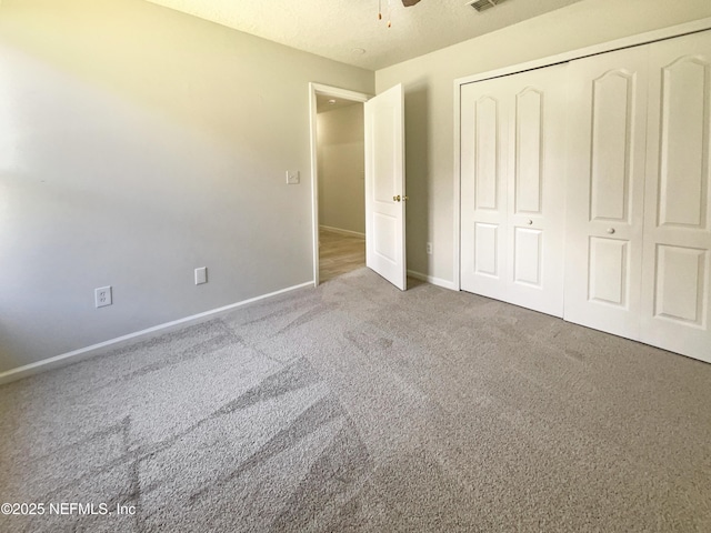 unfurnished bedroom featuring carpet, visible vents, baseboards, a closet, and a textured ceiling