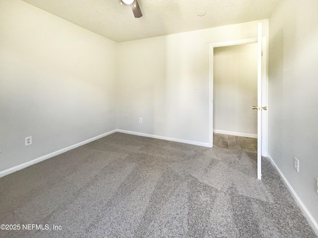 carpeted spare room featuring baseboards, a textured ceiling, and a ceiling fan