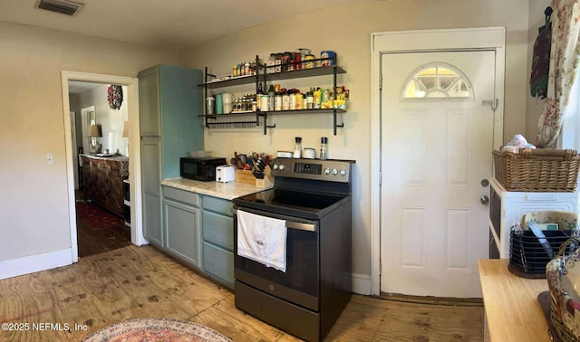 kitchen featuring visible vents, black appliances, light countertops, and light wood-style floors