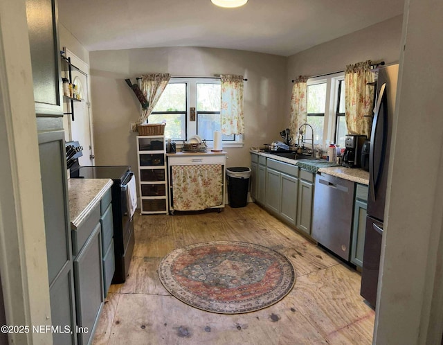 kitchen featuring light wood-type flooring, gray cabinetry, a sink, appliances with stainless steel finishes, and light countertops