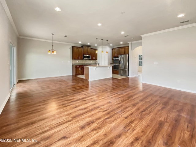 unfurnished living room featuring arched walkways, visible vents, baseboards, and light wood-style floors