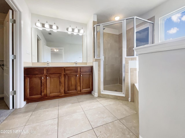 bathroom with tile patterned flooring, a shower stall, double vanity, and a sink