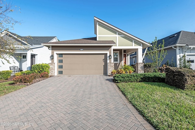 view of front of home featuring brick siding, a front yard, decorative driveway, and a garage