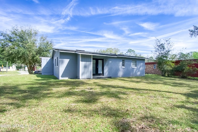 rear view of house featuring a yard, concrete block siding, and french doors