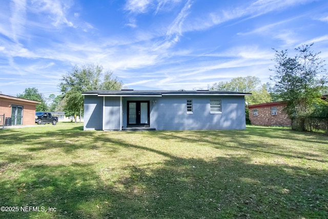 rear view of property featuring a lawn, french doors, and concrete block siding