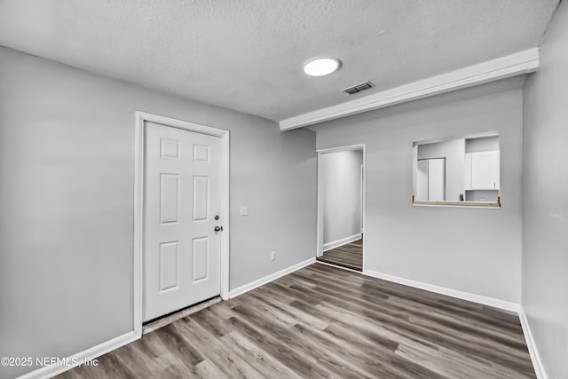 unfurnished room featuring visible vents, wood finished floors, baseboards, and a textured ceiling