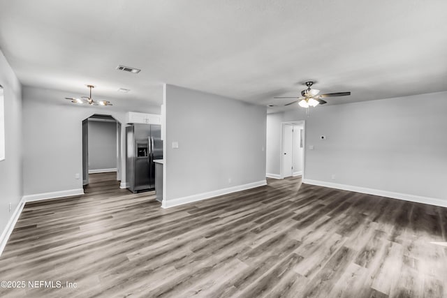 unfurnished living room featuring dark wood finished floors, visible vents, baseboards, and a ceiling fan