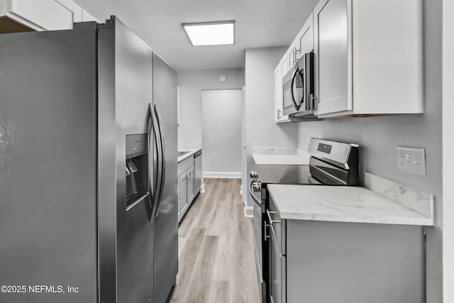 kitchen with stainless steel appliances, light wood-style floors, and gray cabinetry